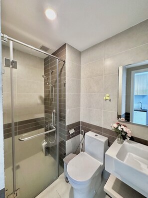 A modern bathroom with a glass shower enclosure, a toilet, and a sink with a mirror. - Saigon Central Apart - Infinity Pool&Gym (Ho Chi Minh City)