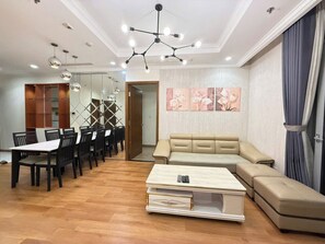 A modern living room with a sofa, a coffee table, and a dining area with chairs and a table. - Saigon Central Apart - Infinity Pool&Gym (Ho Chi Minh City)