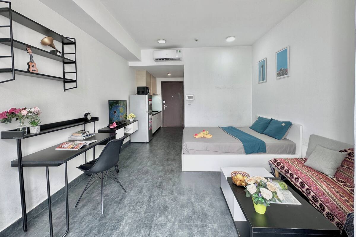 A compact living space with a kitchenette, a dining area, a sofa, and a bed.