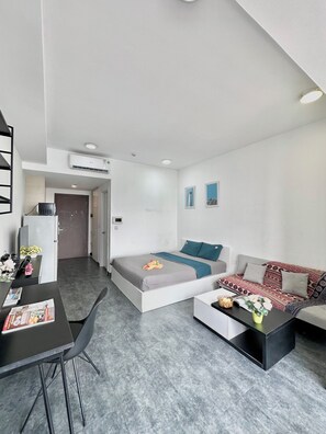 A modern, well-lit room with a bed, a sofa, a dining table, and a kitchenette area. - Saigon Central Apart - Infinity Pool&Gym (Ho Chi Minh City)