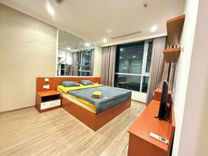 A modern hotel room with a bed, a desk, a TV, and a large window with curtains. - Saigon Central Apart - Infinity Pool&Gym (Ho Chi Minh City)