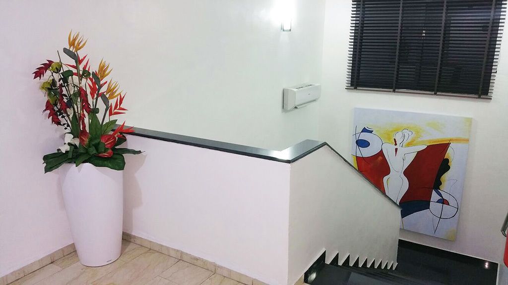 A staircase with a white wall, a potted plant, and a painting.