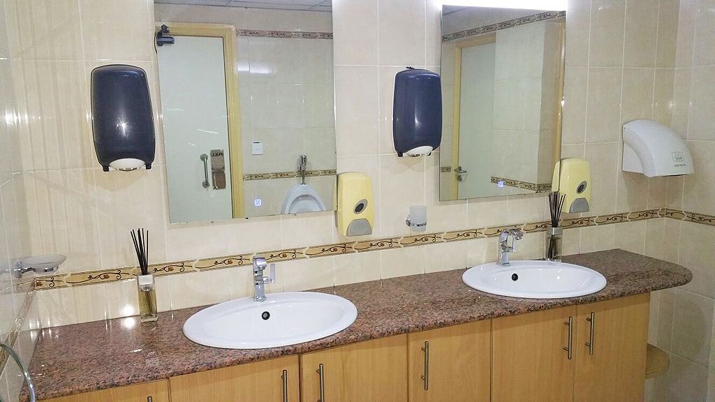 A bathroom with two sinks, a mirror, and two soap dispensers.