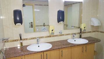 A bathroom with two sinks, a mirror, and two soap dispensers.