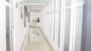 Un pasillo con paredes blancas, ventanas amplias y suelo brillante.