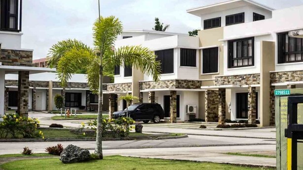A modern multi-story hotel with a stone facade, multiple balconies, and a well-maintained lawn. - Tumon Belair (Tamuning)