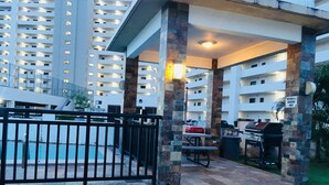 A covered outdoor area with a pool, barbecue setup, and a sign indicating a smoking area. - Tumon Belair (Tamuning)