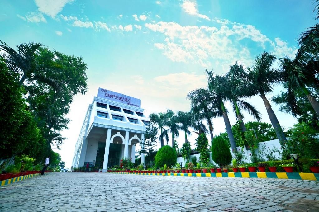 A building with a sign reading 'Imperial' and a paved walkway with palm trees.