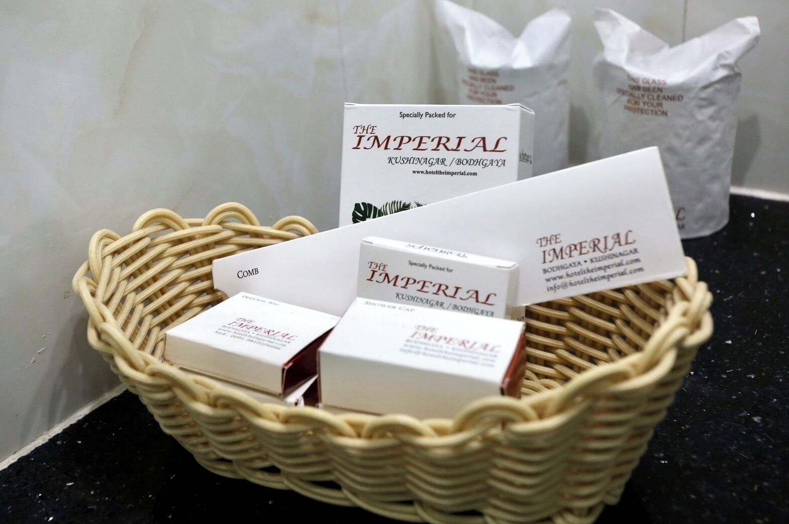 A wicker basket containing several boxes labeled "The Imperial Kushinagar / Bodhgaya" hotel.