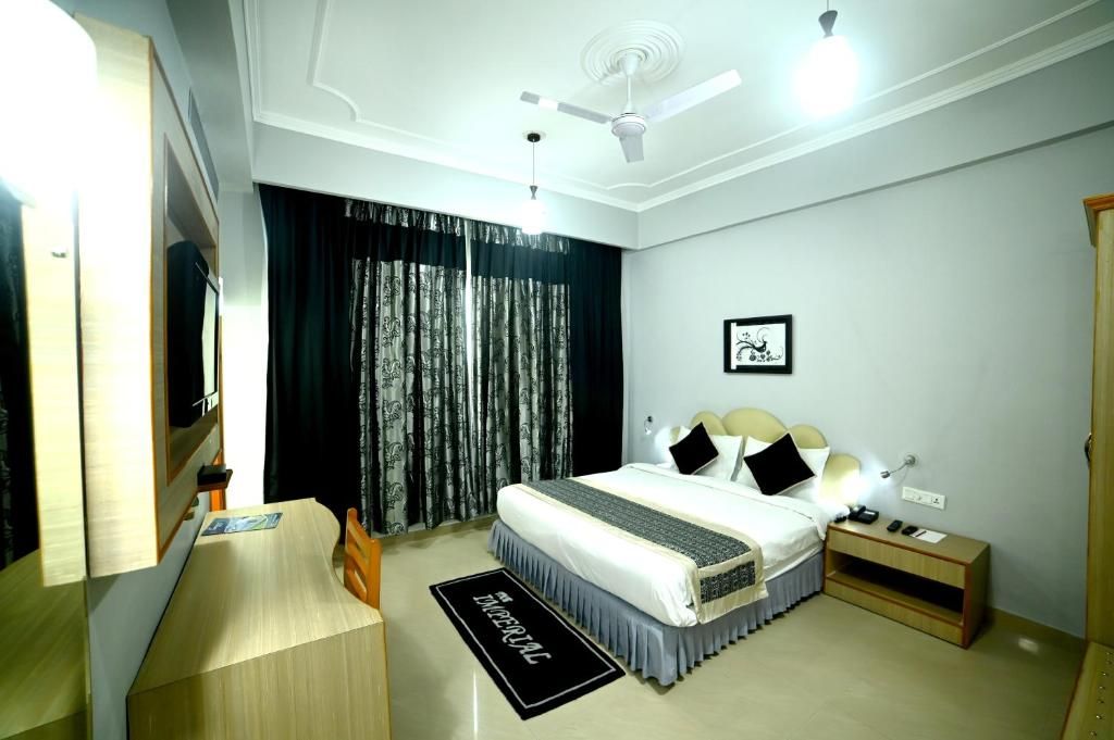 A hotel room with a bed, bedside table, nightstand, and a ceiling fan.