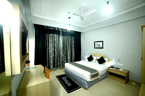 A hotel room with a bed, bedside table, nightstand, and a ceiling fan.