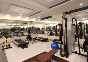 A gym with various exercise equipment including treadmills, ellipticals, and weight machines. - The Imperial Bodhgaya (Gaya)
