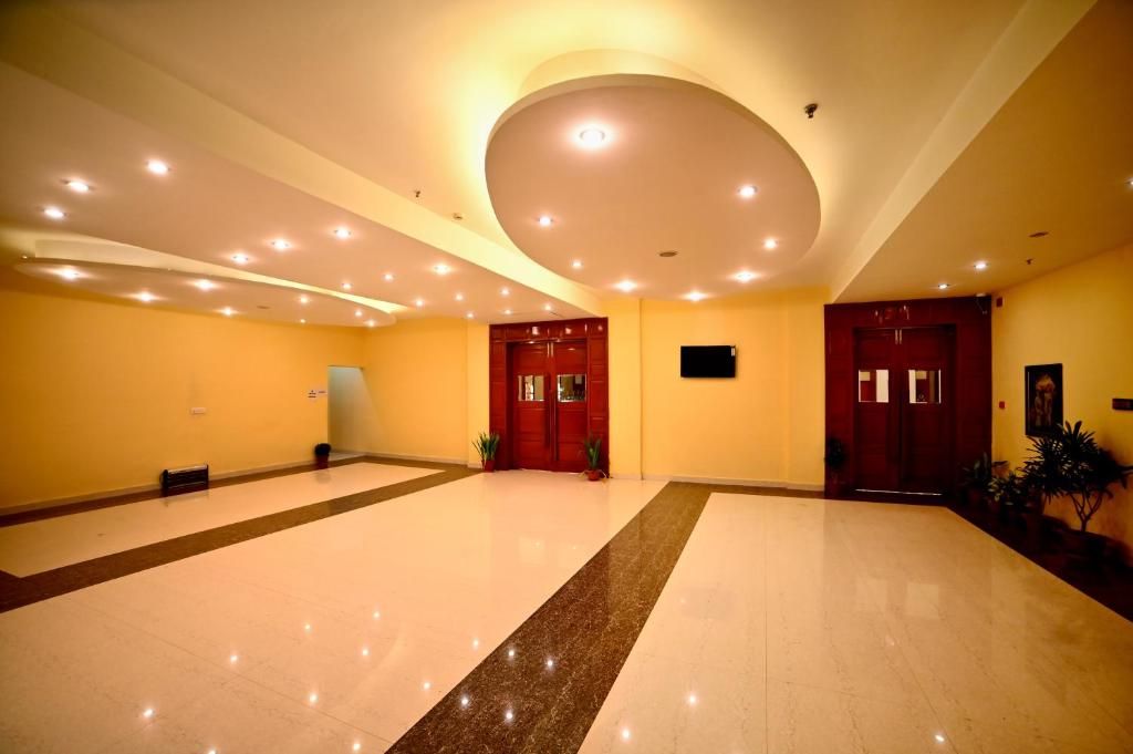 A spacious lobby with a polished floor, a central circular light fixture, and a wooden door.