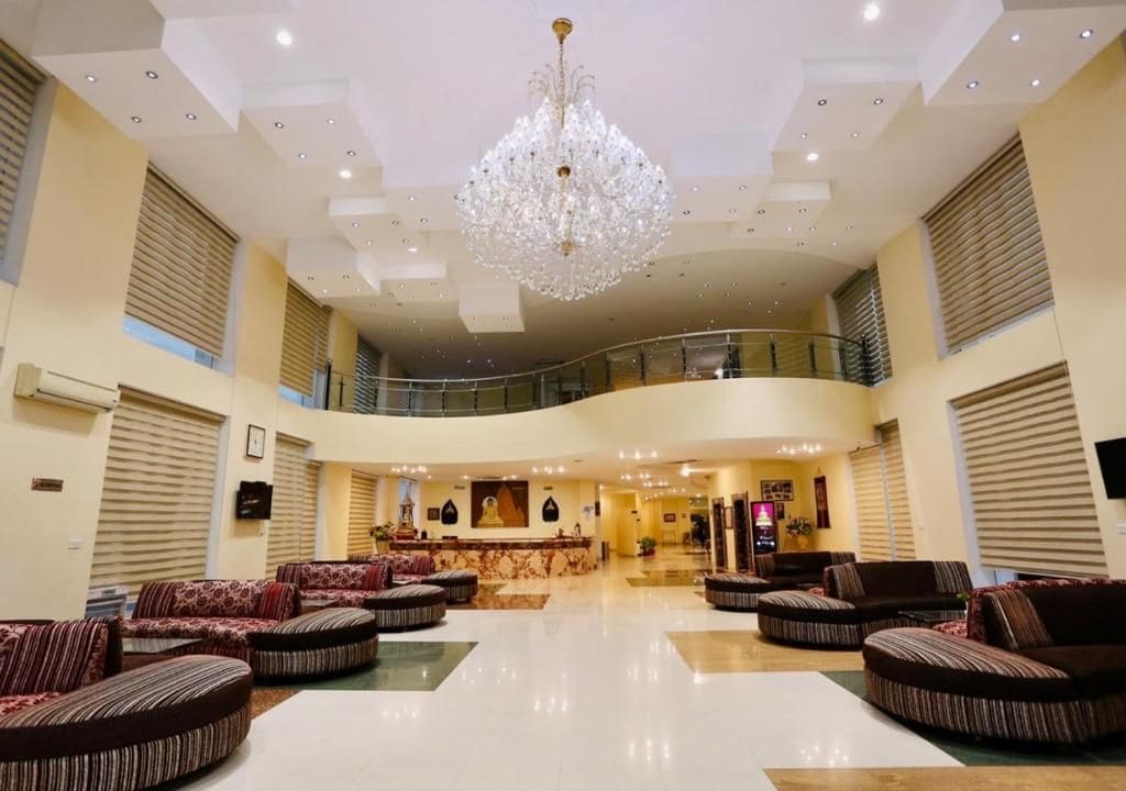 A spacious lobby with a grand chandelier, multiple seating areas, and a central reception desk.