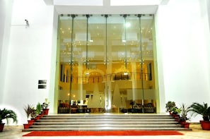 A hotel entrance with a glass facade, steps leading up to it, and potted plants on either side. - The Imperial Bodhgaya (Gaya)