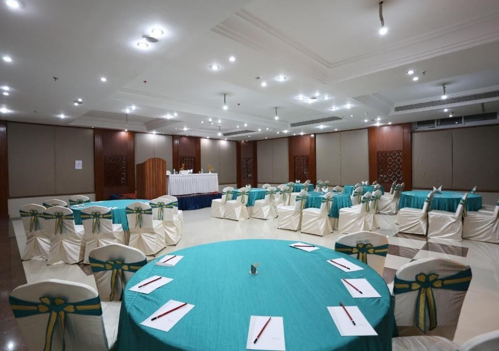Uma sala de conferências com mesas redondas, cadeiras e um púlpito.