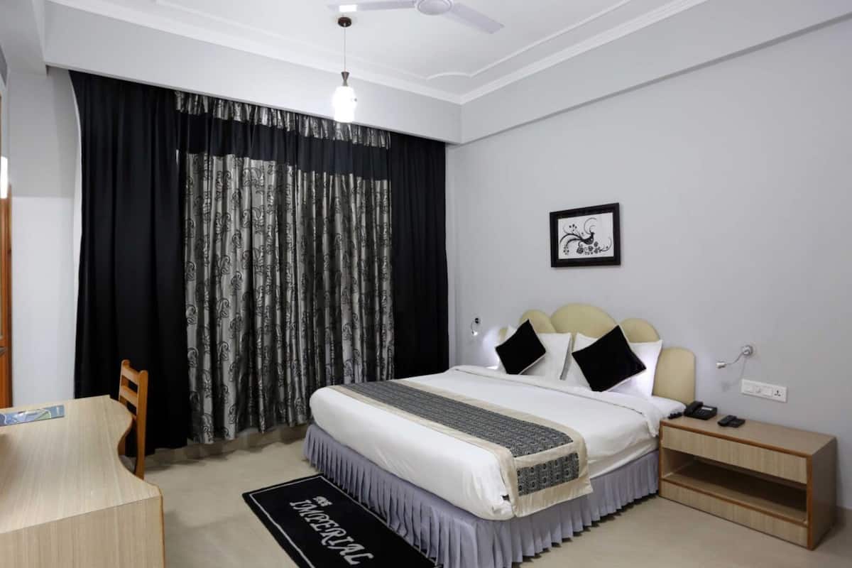 Quarto de hotel com cama, mesa de cabeceira e escrivaninha com cadeira.