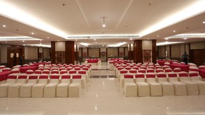 Une grande salle avec des rangées de chaises et de tables, un plancher ciré et une allée centrale.