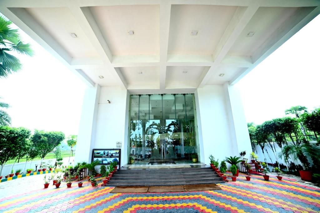 A building entrance with a glass door, steps leading up to it, and potted plants around.