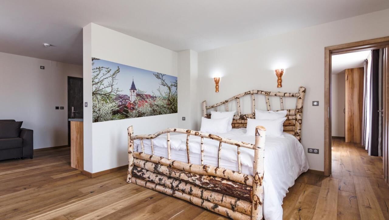 Een slaapkamer met een houten bedframe, een schilderij aan de muur en een houten vloer.