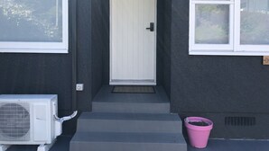 A house with a white door, a small porch, and a pink bucket.