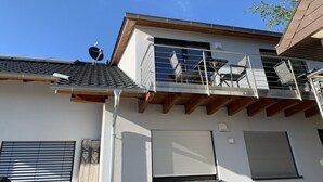 A modern building with a flat roof, a balcony with metal railings, and a satellite dish. - Silvia’s Apartment 2 with a lake view (Goldbach)