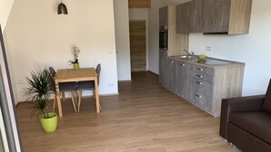 A modern kitchen with grey cabinets, a wooden dining table, and a potted plant. - Silvia’s Apartment 2 with a lake view (Goldbach)