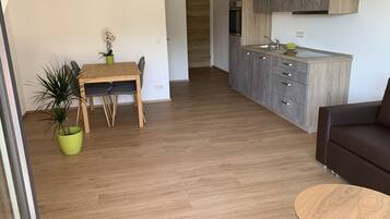 Eine moderne Küche mit grauen Schränken, einem Holztisch und einem Topf mit Pflanze.