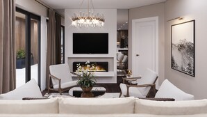 A modern living room with a large flat-screen TV, a chandelier, and a fireplace. - K-Zone The Star Hotel (Hai Phong)