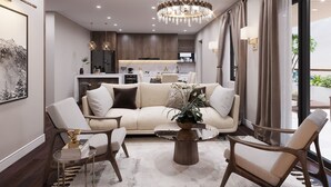 A modern living room with a beige sofa, two armchairs, a coffee table, and a chandelier. - K-Zone The Star Hotel (Hai Phong)