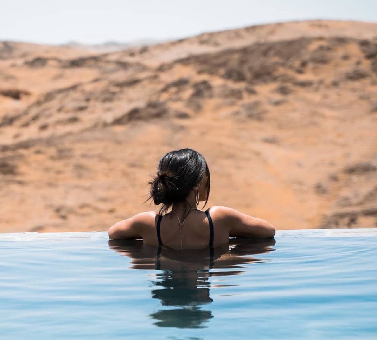 Una persona en una piscina con un paisaje desértico al fondo.