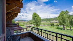 Ein Balkon mit Blick auf eine grüne Landschaft, einer Holzterrasse und einem Metallgeländer.