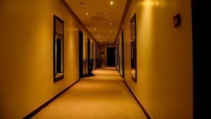 Un couloir d'hôtel avec un sol recouvert de moquette, des murs recouverts de miroirs et un éclairage encastré.