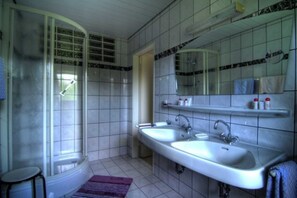 Ein Badezimmer mit Dusche, zwei Waschbecken, einem Spiegel und gefliesten Wänden.