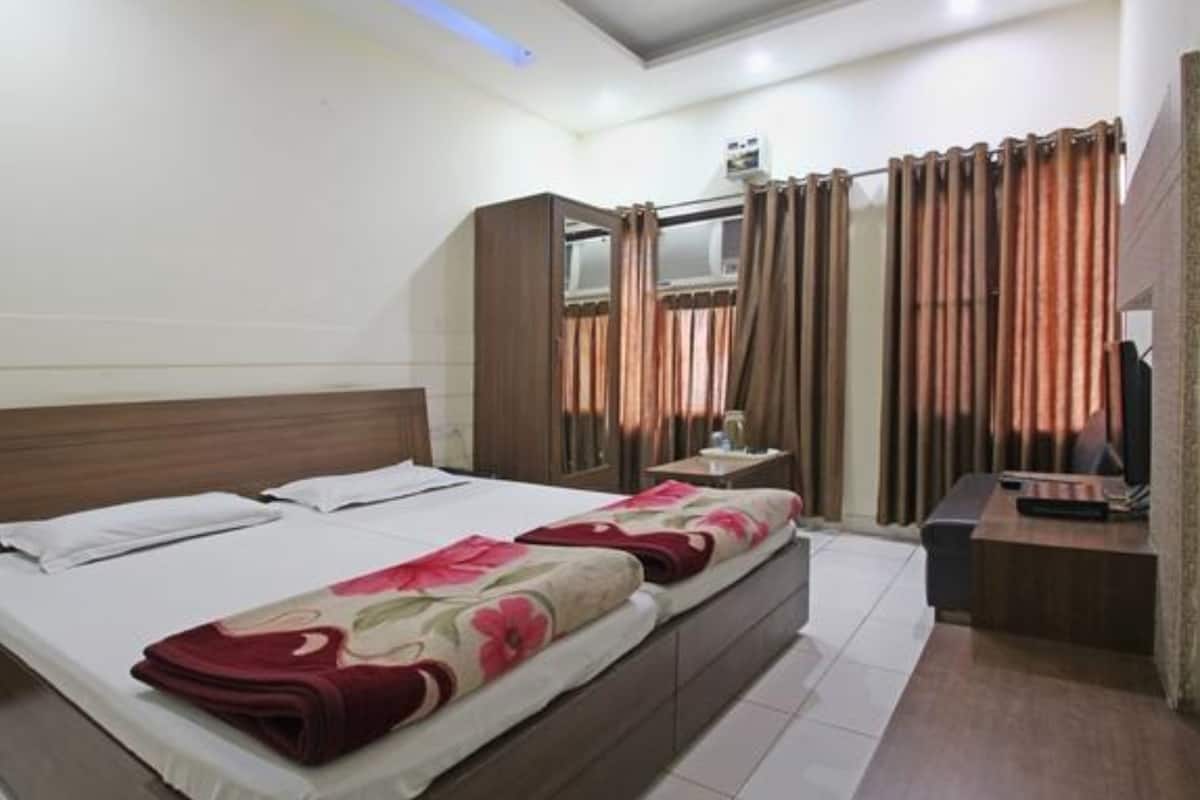 A bedroom with a bed, a desk, and a window with curtains.