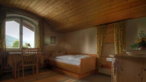 Een slaapkamer met een houten plafond, een bed, een bureau en een raam met gordijnen.