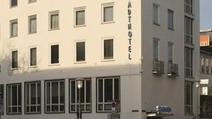 Un edificio de varios pisos con fachada plana, ventanas amplias y un letrero que dice "STADTHOFEL".