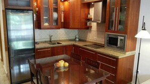 A modern kitchen with wooden cabinets, stainless steel appliances, and a glass dining table with fruits. - Apartment in La Carihuela, Wifi & 20 meters from the beach (Torremolinos)