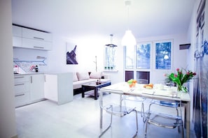 A modern kitchen with a dining area, white cabinetry, a map on the wall, and a view of the Eiffel Tower through the windows. - Apartment Bright & Comfy (Kraków)