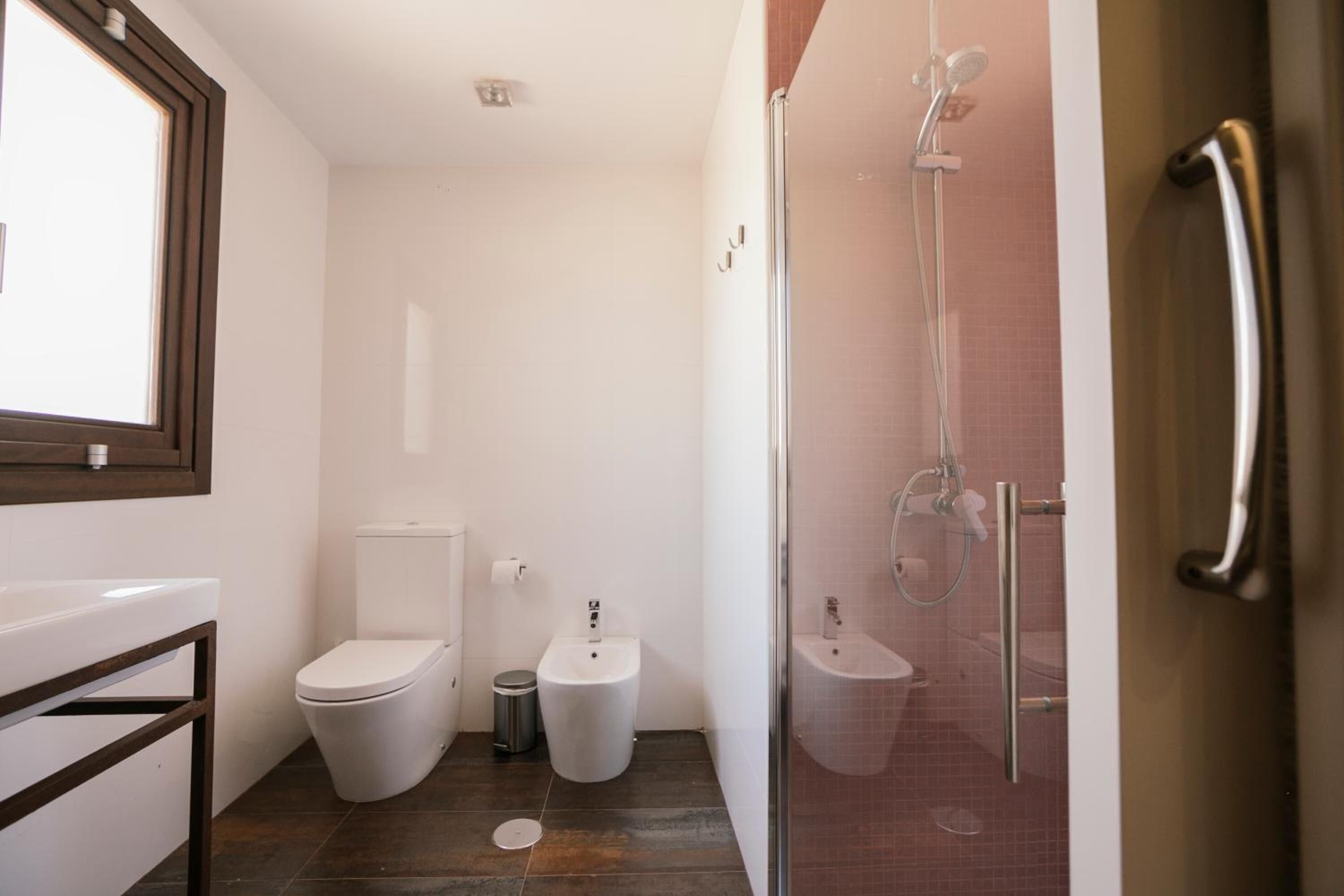 A modern bathroom with a toilet, bidet, and glass-enclosed shower area.