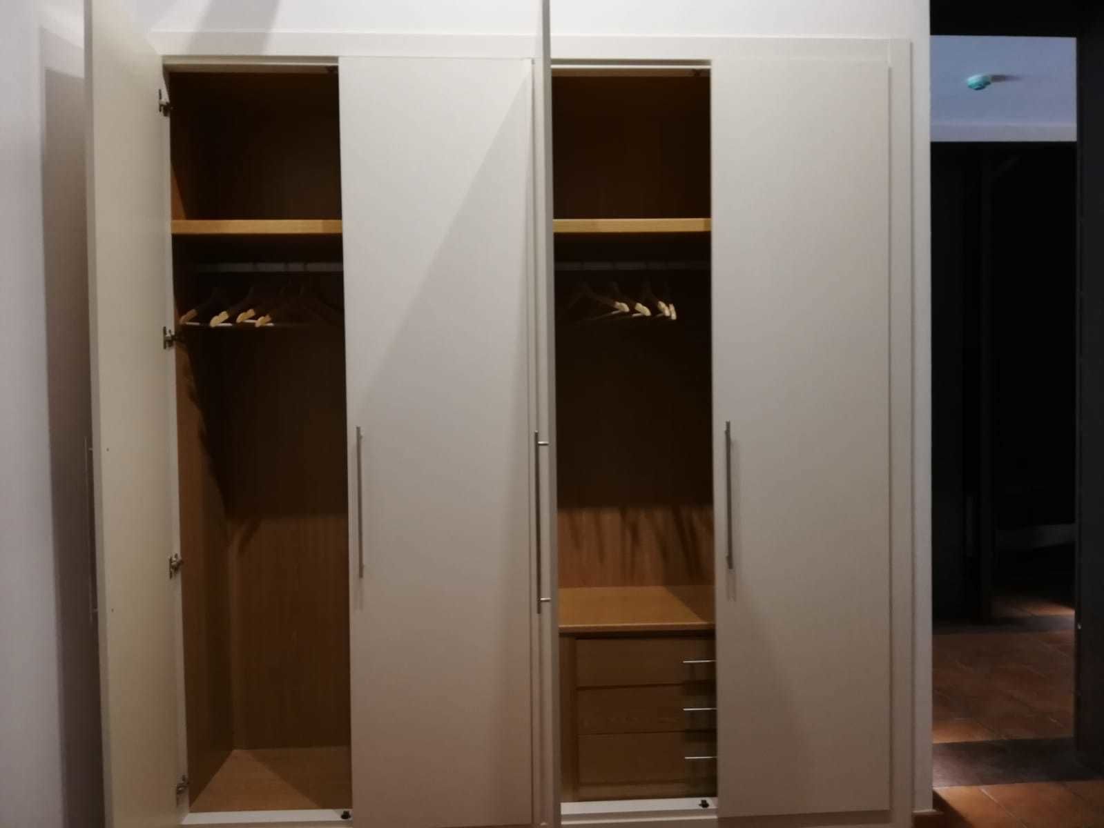 A wardrobe with two doors, a mirror, and a hanging rod.