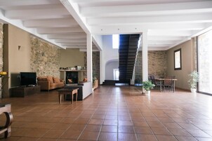 Un amplio salón con chimenea, un sofá, una televisión y un comedor con sillas y una mesa.