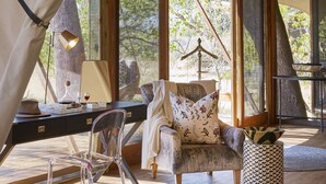 A cozy tented room with a desk, chair, and a cushioned seating area.