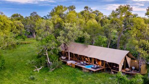 A safari lodge with an open-air design, a swimming pool, and a deck area.