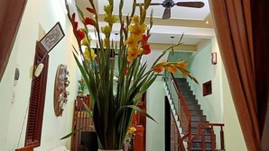 Un soggiorno con un grande vaso di fiori gialli, un tavolo in legno e una scala che conduce a un piano superiore.