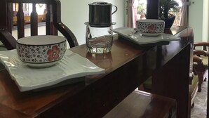 Un'area pranzo con un tavolo di legno, una macchina per caffè, una ciotola e un set di bicchieri da vino.