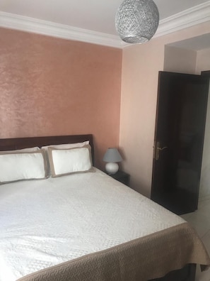 Un dormitorio con una cama, una mesita de noche, una lámpara y un armario.