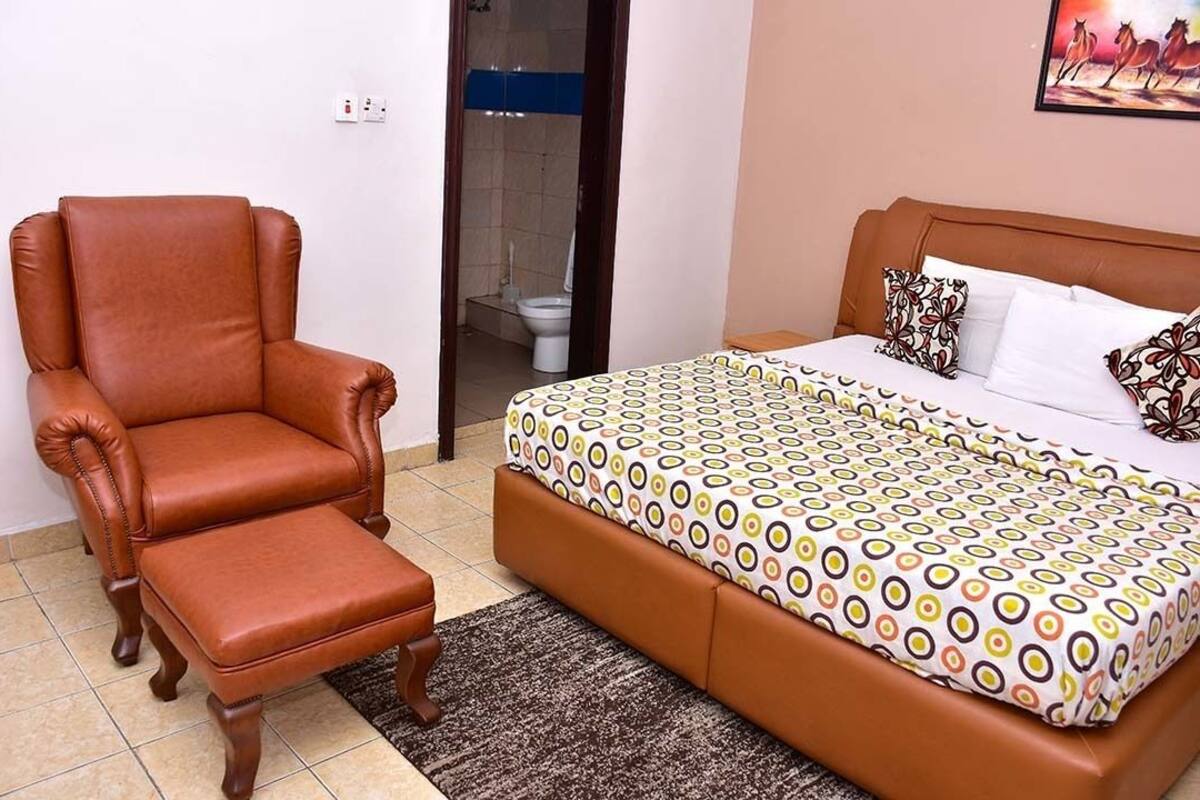 A bedroom with a brown leather armchair, a patterned bedspread, and a small bedside table.