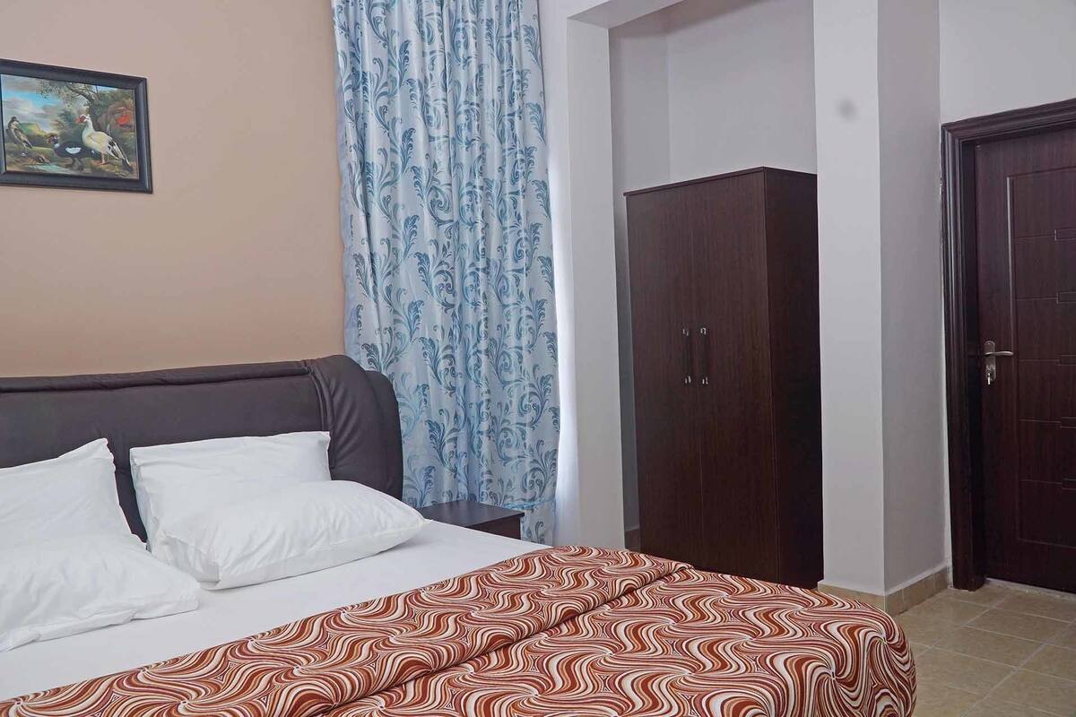 A bedroom with a bed, a wardrobe, and a door.