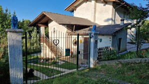 A rustic house with a tiled roof, a stone fence, and a heart-shaped decoration on the gate. - Casa Omnia B&B (Castellamonte)
